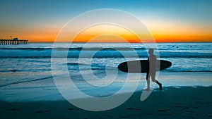 Silhouette of a guy going to surf at the San Clemente beach