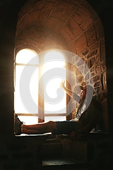 Silhouette of a guy sitting on the window in a Genoese fortress in Sudak Crimea Stone walls of an ancient castle