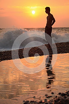 Silhouette guy on sunset wavy beach