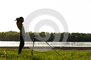 Silhouette of a guy who puts on wireless headphones.  In front of him stands a wireless metal detector supported by a shovel.