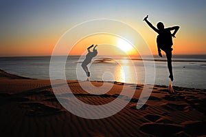 Silhouette of gymnast on beach at sunset