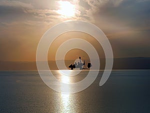Silhouette of Gyrocopter, fun fly, aero sports, skydive, Roto craft, Gyroplane flying against sunset light over the Dead Sea, photo