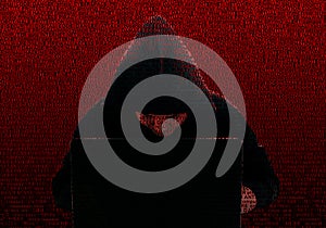 Silhouette of a hacker in a black hood, against the background of computer technology terms. Concept: Theft of digital data,