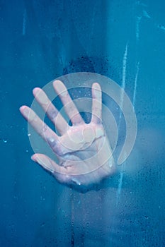 Silhouette of hand behind glass