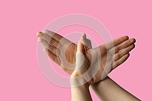 Silhouette of a hand gesture similar to a bird flying on a pink background