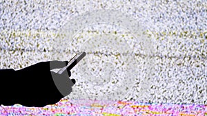 Silhouette of a Hand Holding a Smartphone on TV Screen Background with White Static Noise