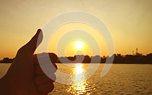 Silhouette of a hand with thumb up on rising sun background