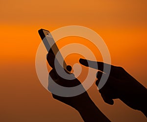 Silhouette of hand using mobile device photo