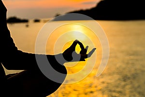 Silhouette, hand of Woman Meditating in Yoga pose or Lotus Posit