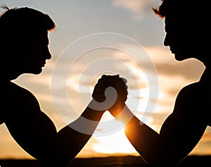 Silhouette of hands that compete in strength. Rivalry, closeup of male arm wrestling. Men measuring forces, arms. Two