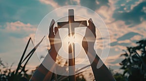 Silhouette of hands and a cross on sunset sky background