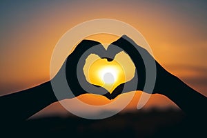 Silhouette of hands forming a heart shape around a sunset, created by Generative AI