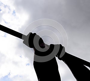 Silhouette of hands on a horizontal bar. Hands on the bar close-up. The man pulls himself up on the bar. Playing sports in the fre