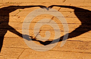 Silhouette of hands making sign heart on wood background