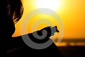 Silhouette of the hands of woman praying to God in the nature witth the Bible at sunset, the concept of religion and spirituality