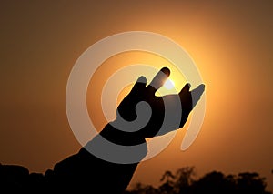 A silhouette hang is trying to touch the Sun.