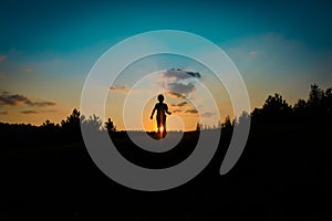 Silhouette of happy boy run and play at sunset