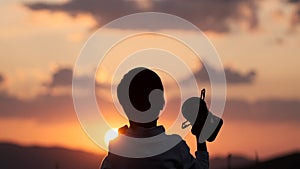 Silhouette of happy champion little boy child holding up golden trophy cup in hand