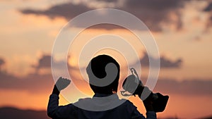 Silhouette of happy champion little boy child holding up golden trophy cup in hand