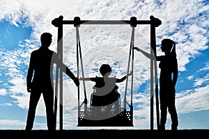 Silhouette of a happy child is a disabled person in a wheelchair on an adaptive swing