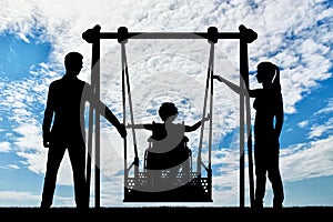 Silhouette of a happy child is a disabled person in a wheelchair on an adaptive swing photo