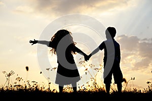 Silhouette, happy children playing on meadow