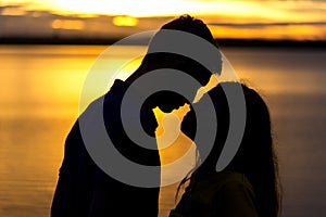 Silhouette of happy couple in love kissing romantic at sunset.