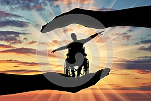 Silhouette of happy disabled man in wheelchair in hands of help