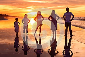 Silhouette of happy diversity generation family holding hands on hips and having fun together on tropical beach at golden sunset