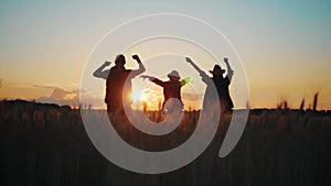 Silhouette happy family farmers in a wheat field at sunset.