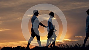 Silhouette of happy family father of mother and two sons playing outdoors in field at sunset