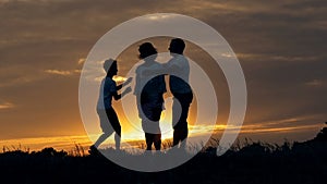 Silhouette of happy family father of mother and two sons playing outdoors in field at sunset