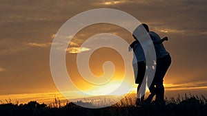 Silhouette of happy family father of mother and two sons playing outdoors in field at sunset