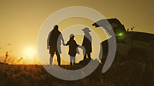 Silhouette the happy family of four people, mother, father and daughter are happy stand on the open trunk of a car at