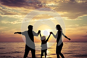 Silhouette of happy family who playing on the beach at the sunset time.