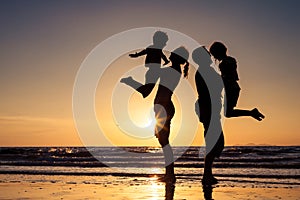 Silhouette of happy family who playing on the beach at the sunset time.