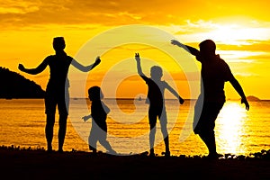 Silhouette of happy family who playing on the beach