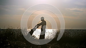 Silhouette happy father and son playing on the beach at sunset. Dad holding his child hands spinning him around