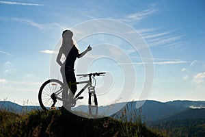 Young happy woman riding bicycle in the mountains at summer day