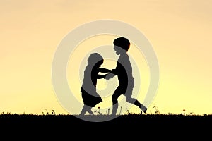 Silhouette of Happy Little Children Dancing at Sunset