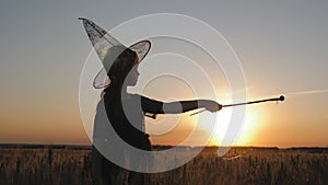 Silhouette of happy little girl dressed in a enchantress costume. The child presents himself as a sorceress, the concept