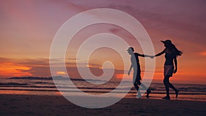 Silhouette of happy loving couple meet and play at the beach on sunset in ocean shore