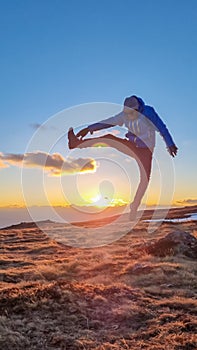 Silhouette of happy man jumping during beautiful sunset on mountain peak Ladinger Spitz, Saualpe, Lavanttal Alps, Carinthia