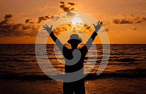 Silhouette of Happy man raise up hands on sunset at sea,Freedom concept