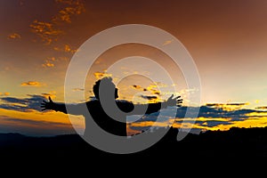 Silhouette Happy Man Standing on Hill at the Sunset on Mountain with Orange Sky. Enjoying Peaceful Moment Concept. Relaxing or