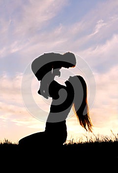 Silhouette of Happy Mother Playing Outside with Baby