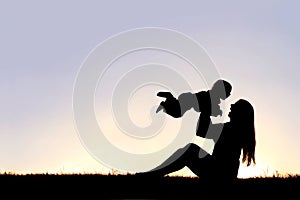 Silhouette of Happy Mother Playing Outside with Laughing Baby