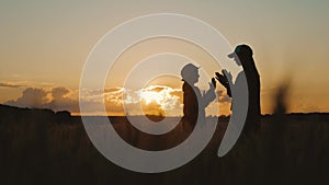 Silhouette happy mothers and daughters playing in a wheat field at sunset. Concept of friendly family.