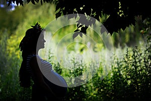 Silhouette of a happy pregnant woman in the garden