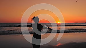 Silhouette of Happy woman on beach at sunset, birds flying over your head